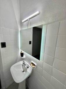 a white bathroom with a sink and a mirror at Departamento con vista al Abasto in Buenos Aires