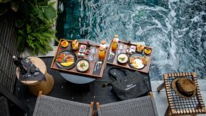 a table with food on it next to a swimming pool at Rhy.a Private Pool Villa in Ko Larn