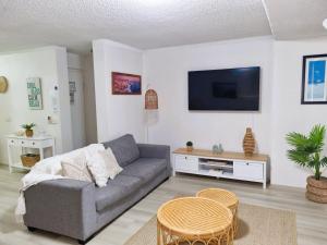 a living room with a couch and a flat screen tv at The Poplars, Pool Access Getaway in Nelson Bay