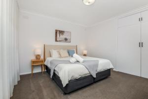 um quarto branco com uma cama grande e lençóis brancos em Charming 3BR Home in Bendigo em Kennington