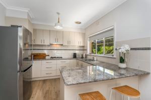 - une cuisine avec des placards blancs et un plan de travail en granit dans l'établissement Charming 3BR Home in Bendigo, à Kennington