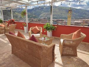 a patio with wicker chairs and a table and a clock tower at Chanka Suites in Talavera