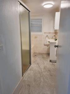 uma casa de banho com um chuveiro e um lavatório. em The Poplars, Pool Access Getaway em Nelson Bay