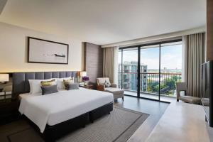 um quarto com uma cama grande e uma janela grande em The Park Nine Hotel Suvarnabhumi em Lat Krabang