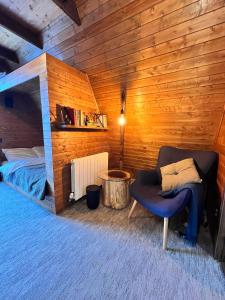 - une chambre avec un lit et une chaise dans l'établissement Chalet A Baisoara - Cabana A-Frame la munte, à Băişoara