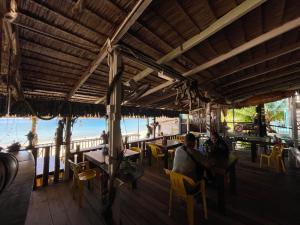 dos personas sentadas en un restaurante en la playa en Beach Shack Chalet - Garden View Aframe Small Unit, en Tioman Island