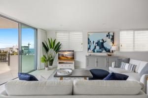 a living room with a couch and a tv at Beachside Stunning 3-Bed with Ocean View & Pool in Caloundra