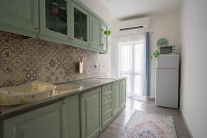 cocina con armarios verdes, fregadero y nevera en Penthouse by the sea, en Sliema
