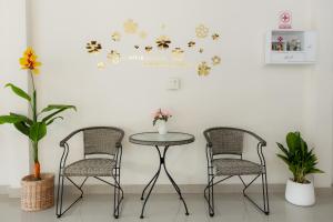 duas cadeiras e uma mesa num quarto com flores na parede em 2B Cozy Hostel ตรัง em Trang