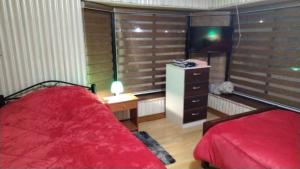a bedroom with a red bed and a dresser with a television at Hotel Aurora in Coronel