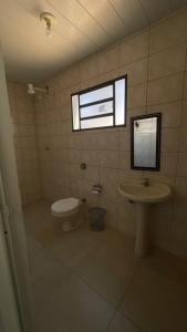 La salle de bains est pourvue d'un lavabo, de toilettes et d'une fenêtre. dans l'établissement Pousada Três Marias Cachoeira Paulista, à Cachoeira Paulista