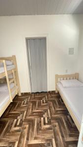 Cette chambre dispose de deux lits et de parquet. dans l'établissement Pousada Três Marias Cachoeira Paulista, à Cachoeira Paulista