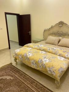 a bedroom with a bed with a yellow blanket with flowers at the beach house in Al Marfaʼ