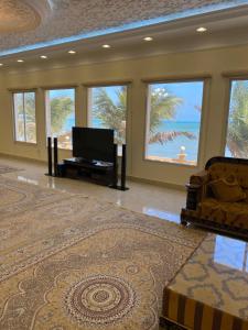 sala de estar con TV, sofá y ventanas en the beach house, en Al Mirfa