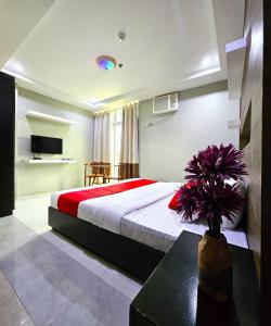 a bedroom with a bed and a table with a vase of flowers at The JRJF Hotel near Tagum Terminal in Tagum