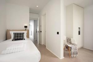 a white bedroom with a bed and a chair at Villa Mirage - Super Paradise beach in Mýkonos City