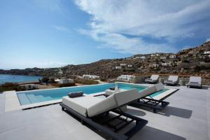 a pool with chaise lounge chairs and a swimming pool at Villa Mirage - Super Paradise beach in Mikonos