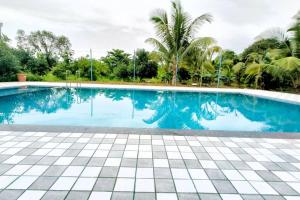 a swimming pool with blue water and palm trees at Mumbai Oasis in Thane