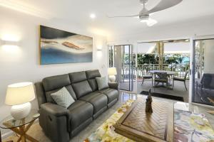 ein Wohnzimmer mit einem Sofa und einem Tisch in der Unterkunft On The Beach Apartments in Trinity Beach