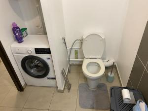 une petite salle de bains avec un lave-linge et des toilettes. dans l'établissement F2 St Denis Jardin d'état, à Saint-Denis