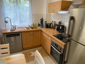 a kitchen with wooden cabinets and a stainless steel refrigerator at F2 St Denis Jardin d'état in Saint-Denis