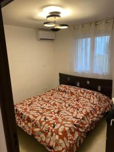 um quarto com uma cama com um edredão vermelho em F2 St Denis Jardin d'état em Saint-Denis