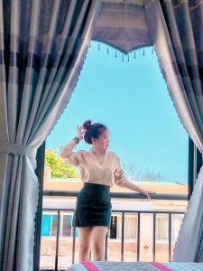 Ly Son的住宿－KHÁCH SẠN HƯNG THỊNH - Lý Sơn，站在窗前的女人