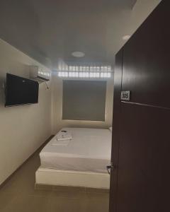 Cette petite chambre comprend un lit et une télévision. dans l'établissement Hotel ZT, à Mariquita