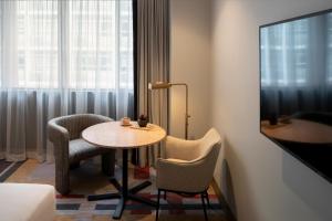 um quarto com uma mesa e cadeiras e uma janela em The Sebel Sydney Martin Place em Sydney