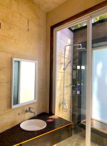 a bathroom with a sink and a glass shower at The LivingSpace Villa in Camotes Islands
