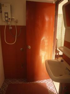 ein Badezimmer mit einem Waschbecken und einer Tür neben einem Spiegel in der Unterkunft Sarah Guest House in Chiang Mai