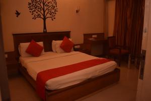 Habitación de hotel con cama con almohadas rojas en HOTEL DHIRAJ en Thane