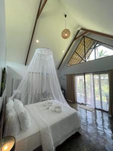 a bedroom with a white bed with a mosquito net at EPBliss Siargao in General Luna