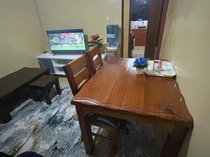 a wooden table and chairs in a room with a television at Tenet Upper Kabete Homes in Nairobi
