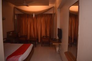 a bedroom with a bed and a desk and a window at HOTEL DHIRAJ in Thane