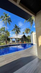 una piscina con palme sullo sfondo di The LivingSpace Villa a Camotes Islands