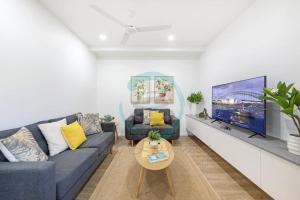 un soggiorno con divano blu e TV a schermo piatto di Zen Cityscape 3BR House at Mitchell Street a Larrakeyah