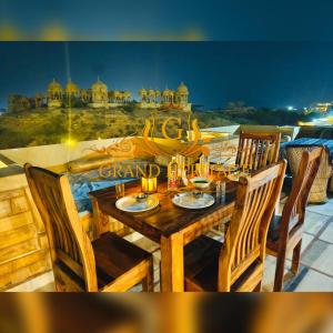 a wooden table and chairs with a view of a city at Hotel Grand Heritage Jaisalmer in Jaisalmer