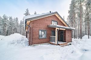 uma cabana de madeira na neve na floresta em Villa Alvo em Kittilä