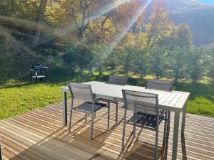 una mesa y sillas en una terraza con parrilla en La Gardette en Le Freney-dʼOisans