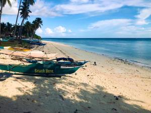 a green boat on a beach with the ocean at The LivingSpace Villa in Camotes Islands