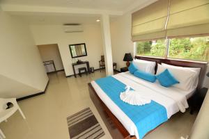 a bedroom with a large bed with blue and white pillows at Kurulu Villa Baddegama in Galle +79 photos