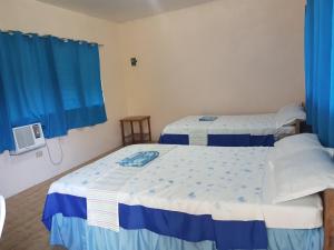 two beds in a room with blue curtains at Aglicay Beach Resort in Romblon