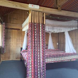 two beds in a wooden room with curtains at Homestay field in Ha Giang