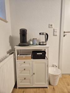 a white cabinet with a coffee maker on top of it at Apartment Tanne in Düsseldorf