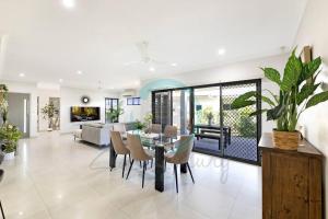 une salle à manger et un salon avec une table et des chaises dans l'établissement Zenhouse Vista Elegant 5BR Coastal Haven, à Leanyer