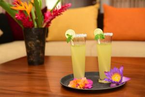 two drinks on a plate on a table with flowers at Kurulu Villa Baddegama in Galle
