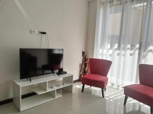 ein Wohnzimmer mit einem TV und 2 roten Stühlen in der Unterkunft Departamento Ambar in Cochabamba