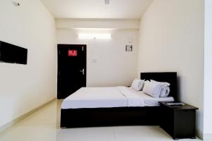 a bedroom with a bed with white sheets and a black door at Hotel O Home Cozy Home in Guwahati