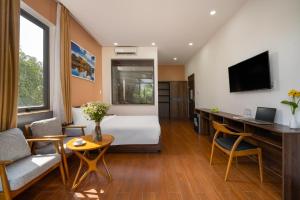 een hotelkamer met een bed en een bureau bij RAON Boutique Villa in Hội An